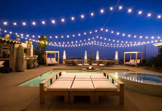 String lighting installed in a beachside property backyard with a pool